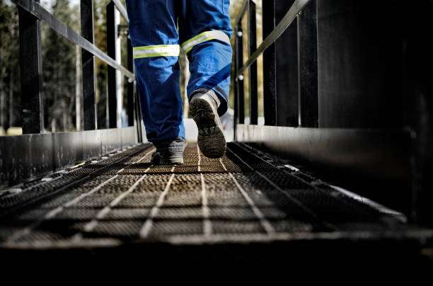 Oil Rig Worker wearing his safety gear walking on a steel walkway