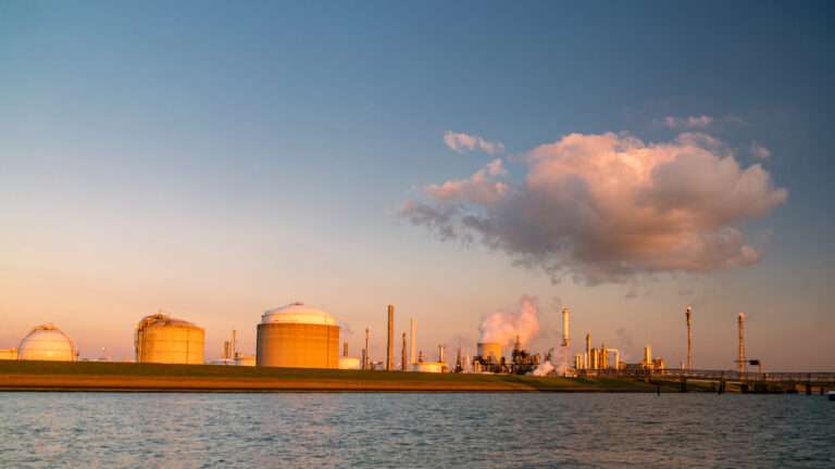 Rotterdam Netherlands, Oil harbor with tank terminals and chemical carriers in the port of Rotterdam during sunrise in the harbor, huge oil tanks to store gas and oil